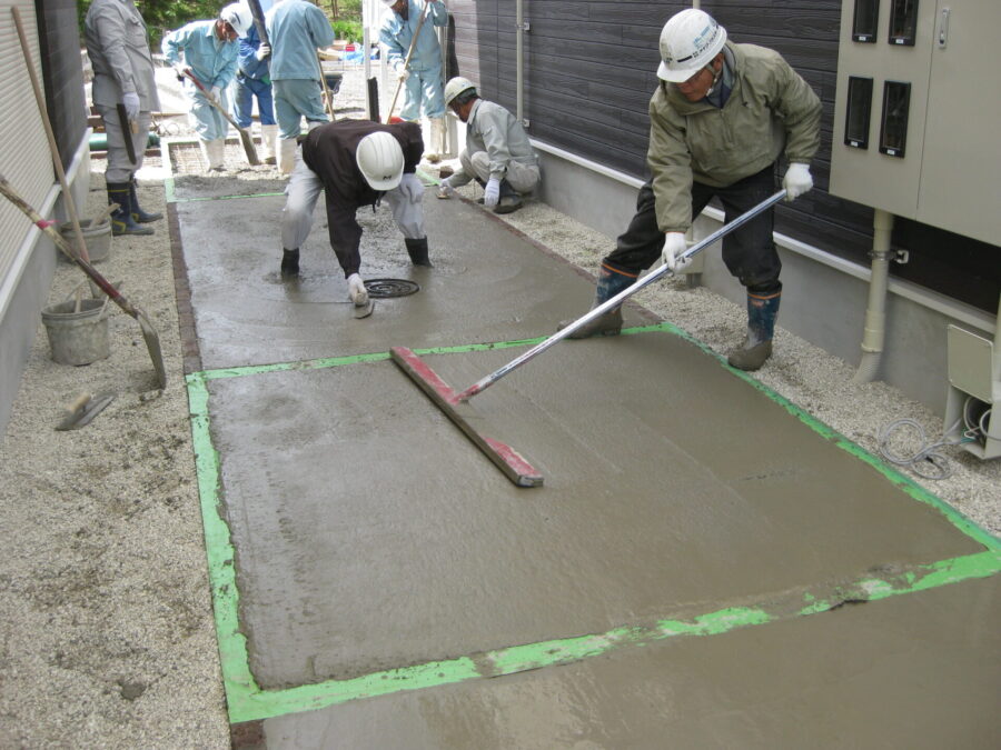 スタンプコンクリートの下地をトンボと金鏝で均す作業（アパートのアプローチ現場）