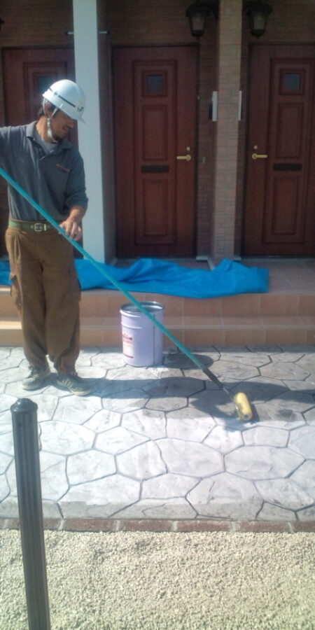 アパートアプローチのスタンプコンクリートにトップコート（シーラー）を塗布する仕上げ作業